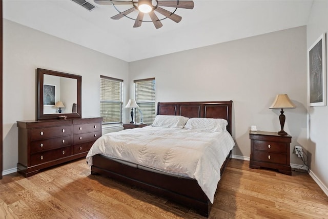 bedroom featuring light wood finished floors, visible vents, ceiling fan, and baseboards