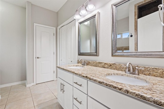 bathroom featuring a sink, baseboards, double vanity, and tile patterned floors