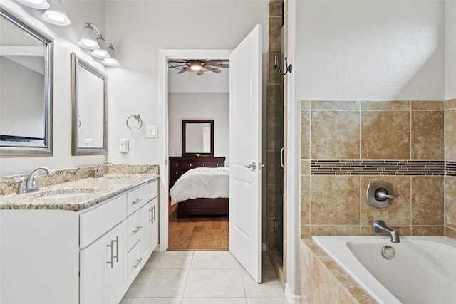 ensuite bathroom featuring tile patterned floors, a tile shower, a relaxing tiled tub, and a sink