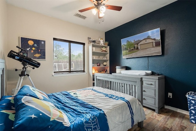 bedroom featuring a ceiling fan, wood finished floors, visible vents, and baseboards