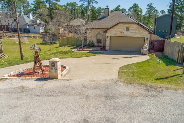 french country style house with stone siding, a trampoline, fence, concrete driveway, and a front yard