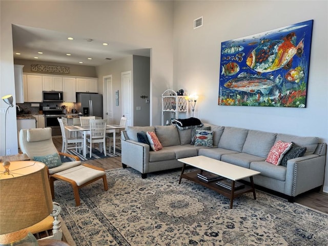 living room with recessed lighting, visible vents, and wood finished floors