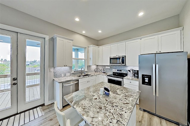 kitchen featuring a sink, white cabinets, french doors, appliances with stainless steel finishes, and tasteful backsplash