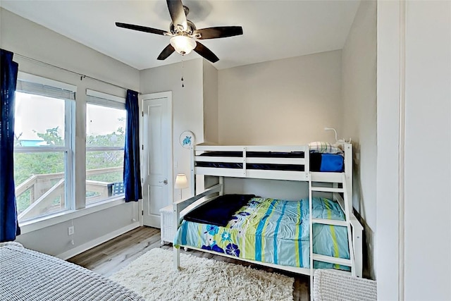 bedroom with a ceiling fan, baseboards, and wood finished floors