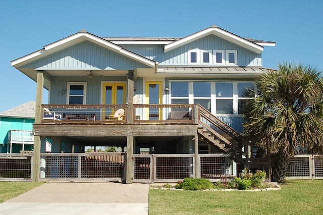 view of front of property featuring driveway, a standing seam roof, fence, metal roof, and ceiling fan