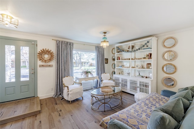 living room with light wood-style flooring, baseboards, and ornamental molding