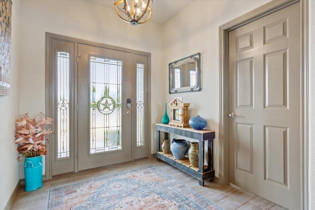 entryway featuring light wood finished floors, baseboards, and an inviting chandelier