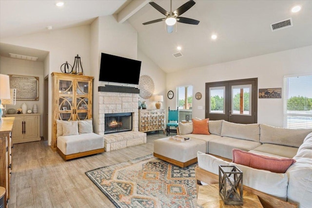 living room featuring light wood finished floors, visible vents, beamed ceiling, a fireplace, and high vaulted ceiling