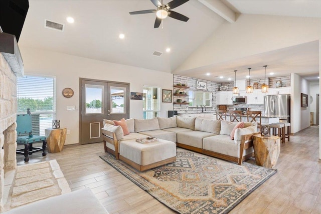 living area featuring visible vents, beamed ceiling, high vaulted ceiling, and light wood-style floors