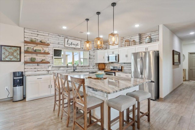 kitchen featuring a breakfast bar, backsplash, appliances with stainless steel finishes, and white cabinetry