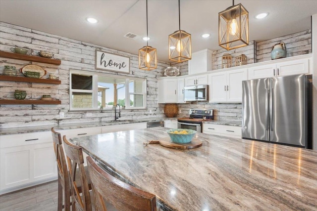 kitchen featuring visible vents, a sink, decorative backsplash, stainless steel appliances, and white cabinetry