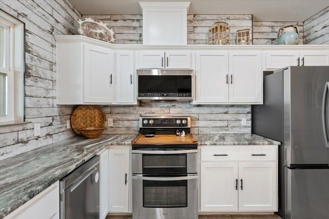 kitchen featuring light stone counters, tasteful backsplash, appliances with stainless steel finishes, and white cabinets