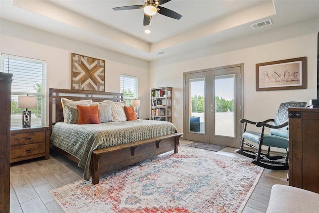 bedroom featuring a raised ceiling, access to outside, multiple windows, and visible vents