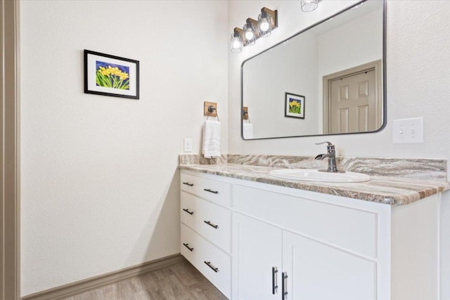 bathroom with baseboards, wood finished floors, and vanity