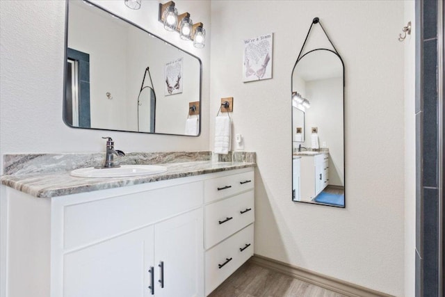 bathroom with baseboards, wood finished floors, and vanity