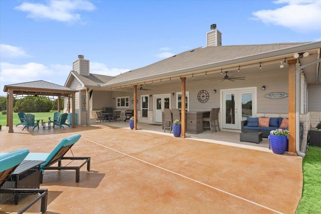 rear view of house featuring a gazebo, french doors, an outdoor living space, and a chimney