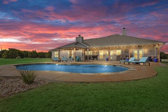 pool with a lawn, french doors, and a patio