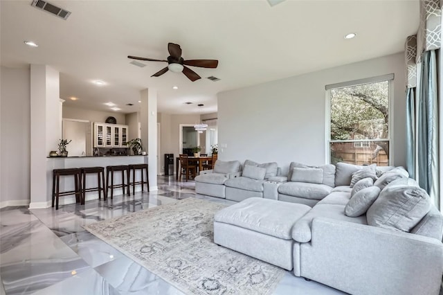 living area with recessed lighting, visible vents, and marble finish floor