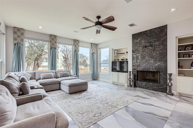 4514 Harvey Penick Dr, Round Rock, TX 78664 - living area with built in shelves, a ceiling fan, recessed lighting, marble tiled floors, and a high end fireplace