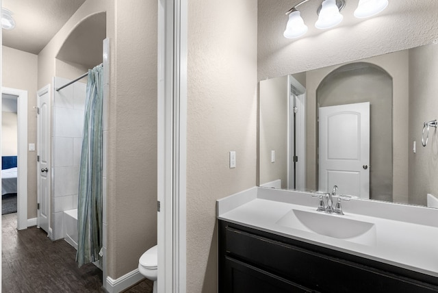 397 Arapaho Dr, Kyle, TX 78640 - bathroom featuring baseboards, toilet, wood finished floors, vanity, and shower / bathtub combination with curtain