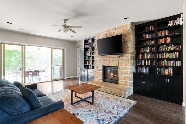 397 Arapaho Dr, Kyle, TX 78640 - living area with built in shelves, baseboards, a fireplace, wood finished floors, and a textured ceiling
