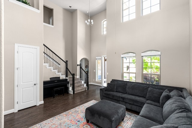 397 Arapaho Dr, Kyle, TX 78640 - living room featuring dark wood-type flooring, arched walkways, an inviting chandelier, baseboards, and stairs