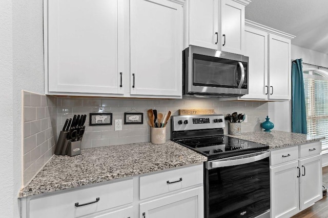 kitchen featuring light stone counters, backsplash, appliances with stainless steel finishes, and white cabinets