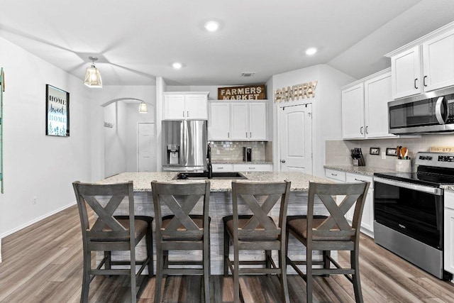 kitchen featuring white cabinets, appliances with stainless steel finishes, a breakfast bar, and a sink