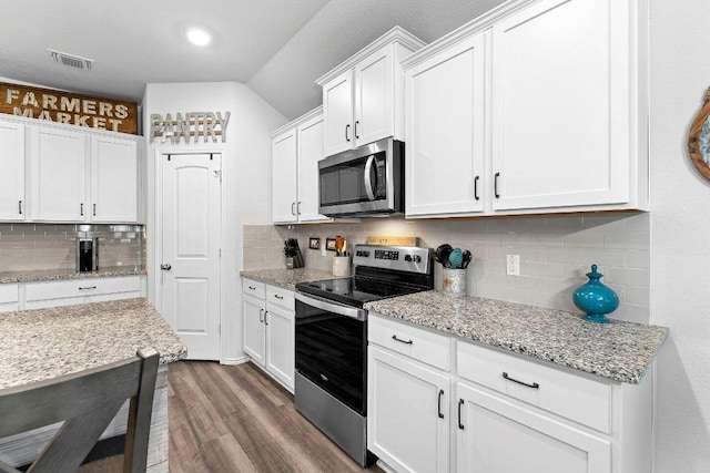 kitchen with dark wood-style floors, visible vents, stainless steel appliances, decorative backsplash, and white cabinets