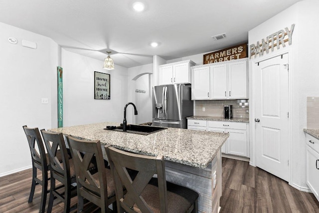 kitchen with visible vents, dark wood finished floors, a sink, decorative backsplash, and stainless steel fridge