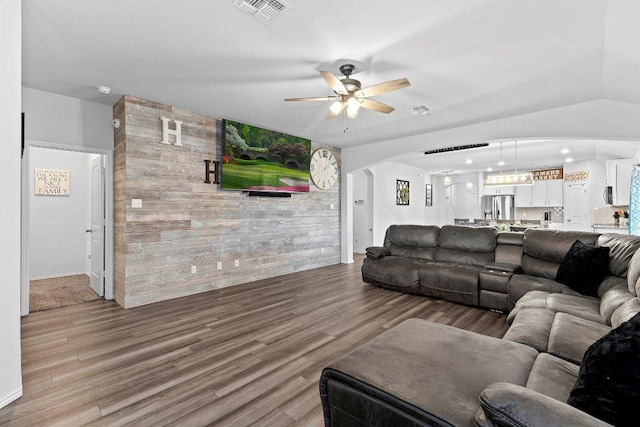 living room featuring arched walkways, visible vents, a ceiling fan, and wood finished floors