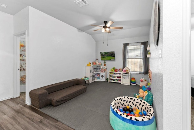 playroom featuring a ceiling fan, vaulted ceiling, wood finished floors, and visible vents