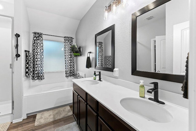 full bathroom with a sink, a garden tub, wood finished floors, and double vanity