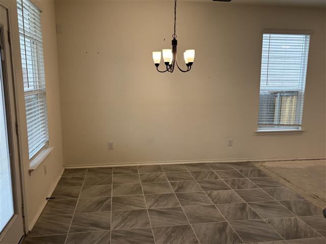 unfurnished room featuring a notable chandelier and baseboards