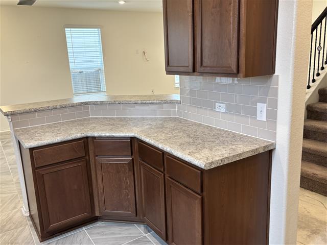 kitchen with tasteful backsplash, a peninsula, dark brown cabinetry, and light countertops