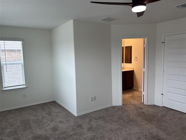 unfurnished room with baseboards, visible vents, a ceiling fan, and carpet