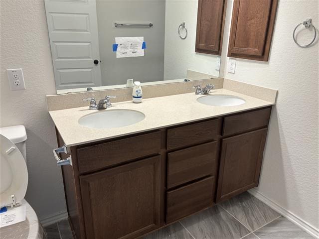 bathroom with a sink, toilet, and double vanity