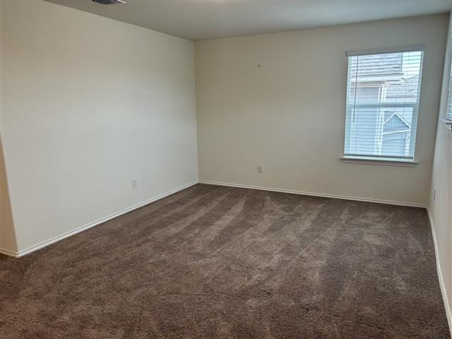 unfurnished room with dark carpet and baseboards