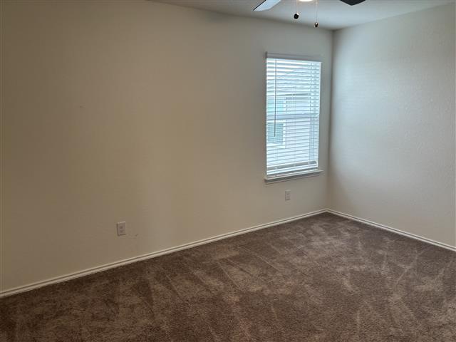 unfurnished room featuring a ceiling fan and dark carpet