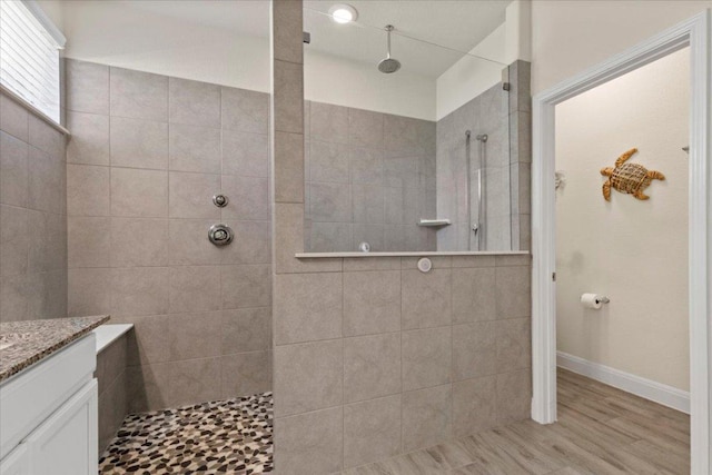 bathroom featuring vanity, wood finished floors, a walk in shower, and baseboards