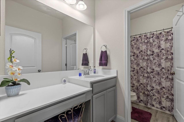 bathroom with toilet, vanity, a shower with shower curtain, and wood finished floors