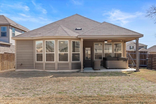 back of property featuring a shingled roof, a yard, a fenced backyard, and a hot tub