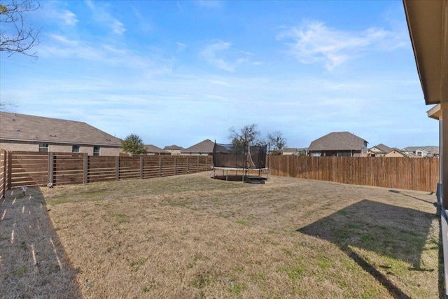 view of yard with a trampoline and a fenced backyard