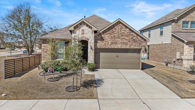 french country style house with brick siding, fence, concrete driveway, a garage, and stone siding