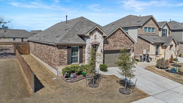 french provincial home with brick siding, fence, a garage, stone siding, and driveway