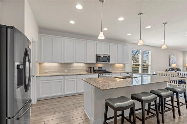 kitchen featuring tasteful backsplash, white cabinets, appliances with stainless steel finishes, and a sink