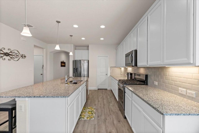 kitchen with light wood finished floors, visible vents, backsplash, stainless steel appliances, and a sink