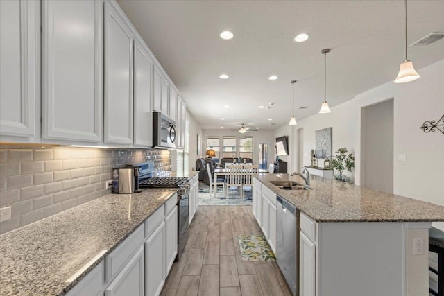 kitchen featuring recessed lighting, a sink, decorative backsplash, light wood-style floors, and appliances with stainless steel finishes