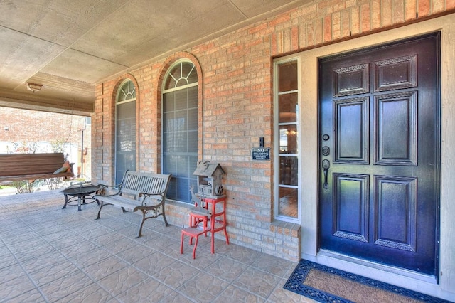 property entrance featuring brick siding and covered porch