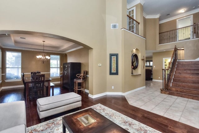 living area with visible vents, stairway, hardwood / wood-style floors, arched walkways, and a raised ceiling